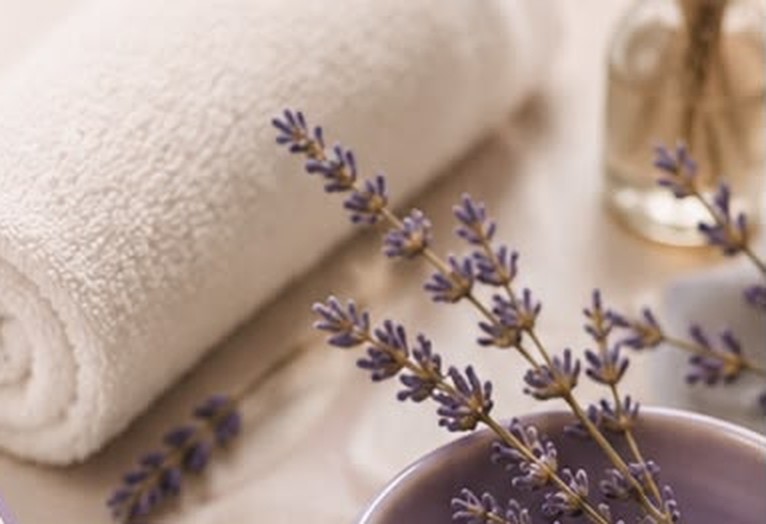 Toalha branca enrolada e ramos de lavanda